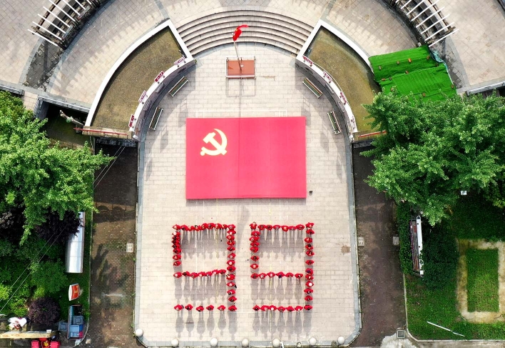 党员们在巨幅党旗前摆出"99"字样.